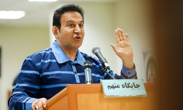  حسین هدایتی با دستبند و ماسک در راهرو دادگاه کیفری تهران