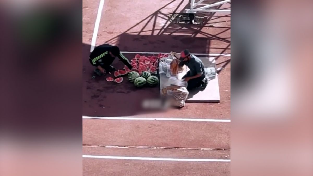 ترمیم چمن ورزشگاه آزادی با دست توسط برخی افراد و تقسیم هندوانه و نان برای تغذیه آن ها